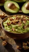 Wooden bowl of creamy guacamole topped with crunchy walnut, surrounded by fresh avocado photo