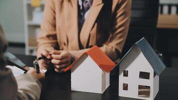 A woman is signing a contract with a house model video