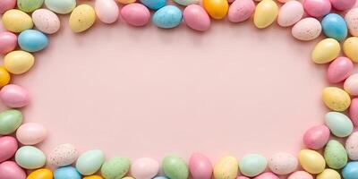 Flat lay composition of pastel-colored Easter eggs forming a frame on a pink background. Holiday mockup with copy space photo