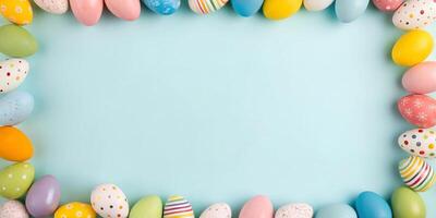Colorful Easter eggs arranged in a frame on a blue background. Flat lay holiday mockup with copy space photo