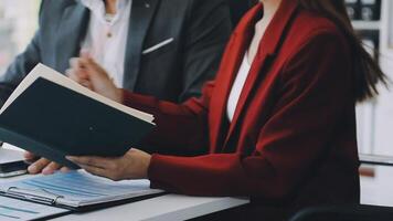 A man and woman are sitting at a desk with a book video