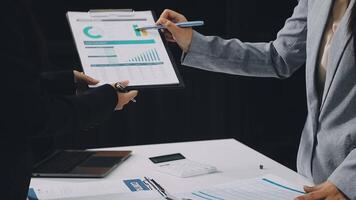 Two business people are holding a clipboard and looking at a chart video