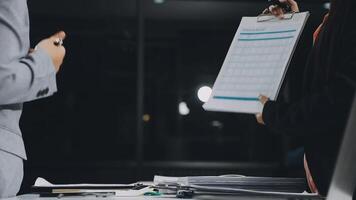 Two business people are standing over a desk with a clipboard video