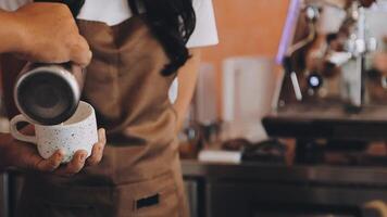 A person in an apron pouring coffee into a cup video