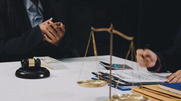 A lawyer and a client are sitting at a table with a scale and money video