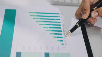 A person is using a pen to write on a paper with a graph on it video