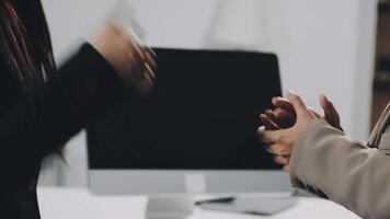 Two business people shaking hands in front of a computer video