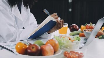 A woman in a lab coat is writing on a notebook video