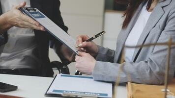 A man and woman are signing paperwork at a desk video