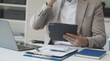 A man in a suit holding a tablet computer and a laptop video