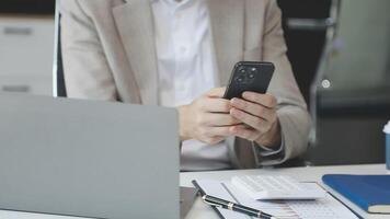 A man in a suit holding a cell phone while sitting at a desk video