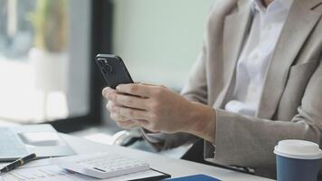 A man in a suit is using his phone while sitting at a desk video