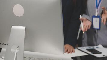 A group of people standing around a computer monitor video