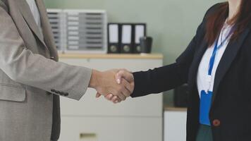 Two business people shaking hands in an office video
