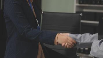 A man and woman shaking hands in an office video