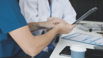 A doctor is using a tablet while another person looks on video