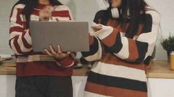 Two women in sweaters holding a laptop video