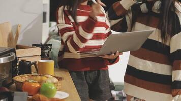 Two women standing in front of a laptop computer video