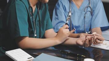 Two doctors are sitting at a table with a pen and paper video