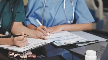 Two doctors are writing on a notebook video