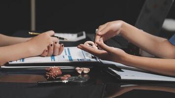 Two people sitting at a table with a pen and a small object video