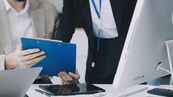 Two people are working on a computer and one is holding a clipboard video