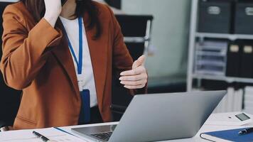 A woman in a business suit is talking on the phone while sitting at a desk video