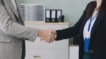 Two business people shaking hands in an office video