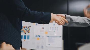 Two business people shaking hands in front of a board video