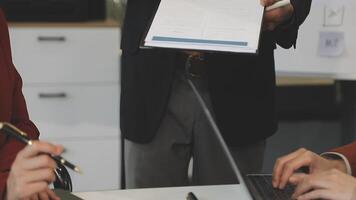 A man is holding a piece of paper while two other people look on video