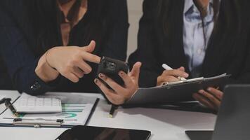 Two business people are using their phones while sitting at a desk video