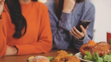 Two women sitting at a table with food and a cell phone video