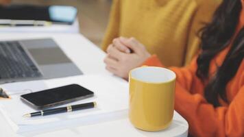 A woman sitting at a desk with a laptop and a coffee cup video