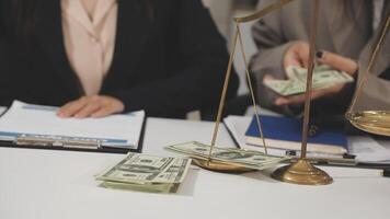 Two business people sitting at a table with money on the scales video