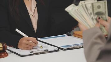 A woman in a business suit is holding money while sitting at a desk video