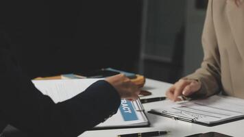 Two people sitting at a table with papers and a pen video