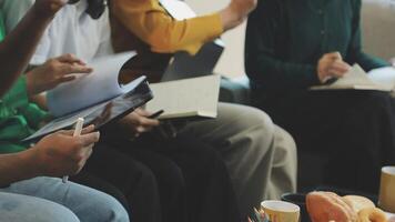 A group of people sitting around a table with books and papers video