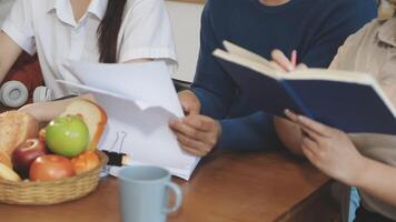 A group of people sitting at a table with a basket of fruit and papers video