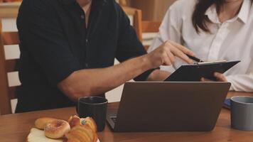 A man and woman are working on a laptop while sitting at a table video