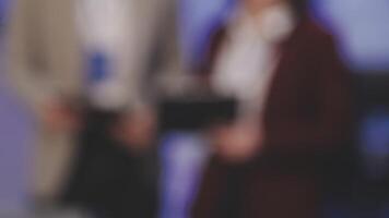 Blurred image of business people standing in front of a screen video