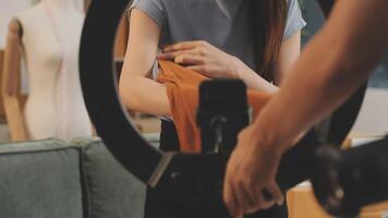 A woman is holding a camera while standing in front of a mirror video