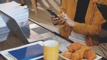 A woman is using her laptop while sitting at a table with a stack of papers video