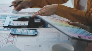 A person is working on a design project with a tablet and a phone video