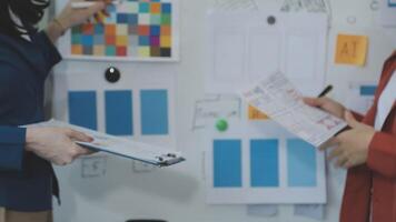 Two people standing in front of a whiteboard with papers on it video