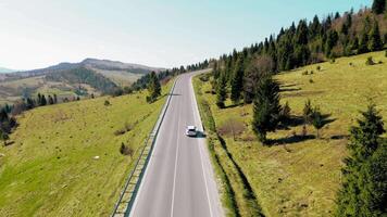 Aerial view white car travels in beautiful mountainous terrain. One car driving on an asphalt road with a beautiful landscape. video