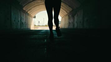 woman running in a dark tunnel to meet the light. Silhouette of a woman from behind running to the light. video