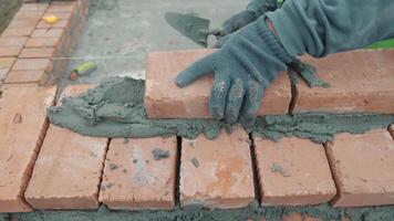 Bricklayer placing bricks with mortar during construction, Worker using gloves to lay bricks and apply mortar for a wall. video