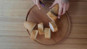 Woman slicing baguette on a wooden plate, Hand using a knife to cut a baguette into slices on a wooden plate. video
