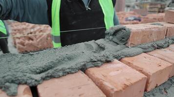 Worker aligning mortar and bricks at a construction site, Close-up of a worker spreading and aligning mortar on bricks. video