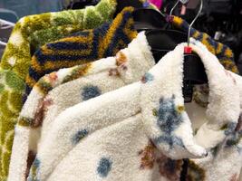 Cozy fleece jackets on hangers displaying varied colors and patterns in clothing store photo